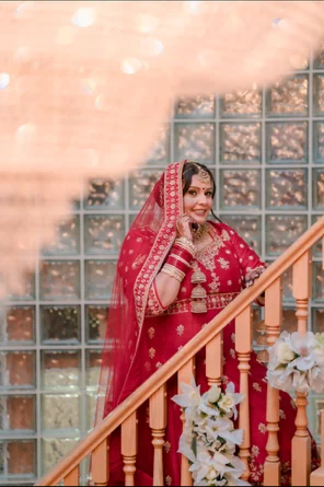 Bride in red traditional wedding attire on a staircase